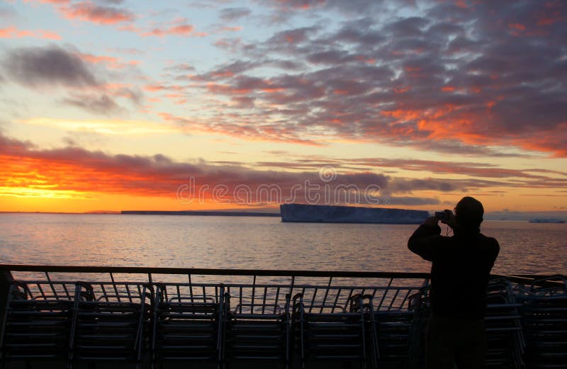 Cruise ship passengers taking pictures of sunset with tabular iceberg, Bransfield Strait, Antarctica. Cruise ship passengers taking pictures of sunset with tabular iceberg, Bransfield Strait, Antarctica