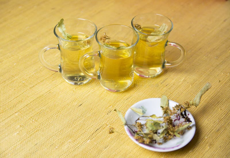 Kräuterlinden-Tee, entzündungshemmender Tee in Gläser Trockene Leinenblüte auf einer Untertasse stockfotografie