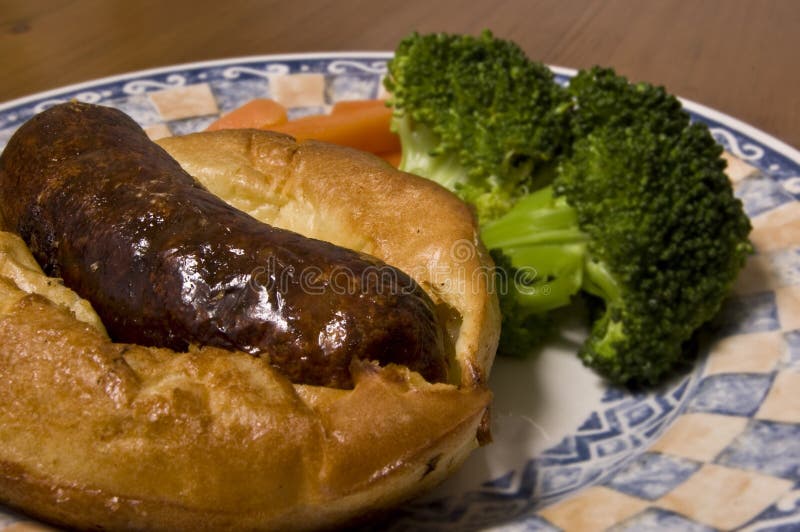 Toad in the hole (British meal of sausage in batter) served with brocolli and carrots. Toad in the hole (British meal of sausage in batter) served with brocolli and carrots