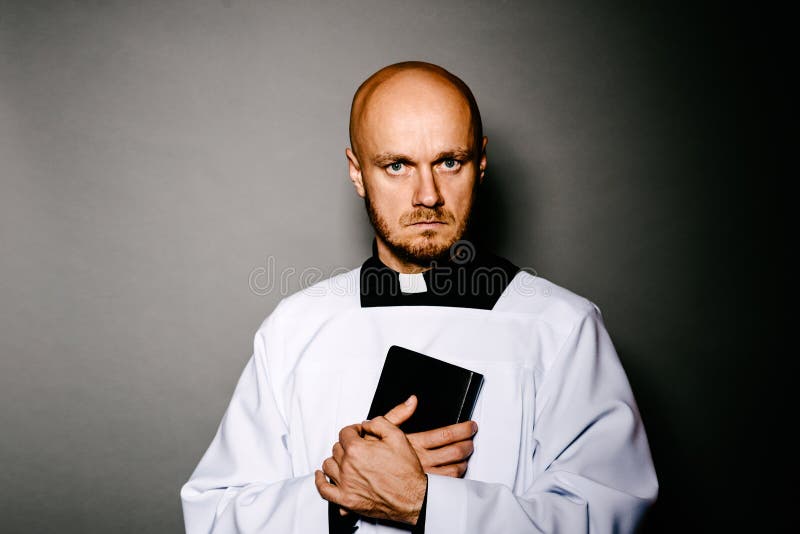 Ksiądz katolicki w białej komży mienia biblii