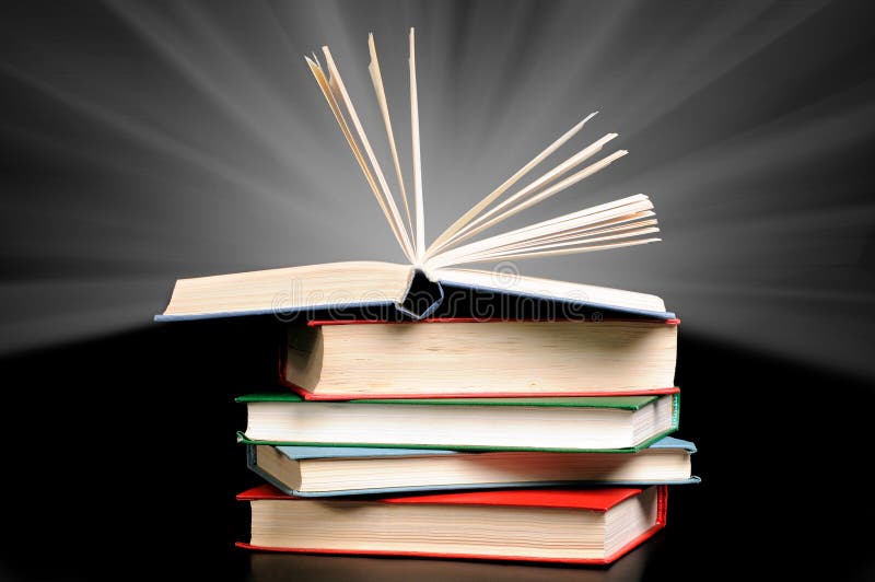 Stack of books and rays of light on black background. Stack of books and rays of light on black background