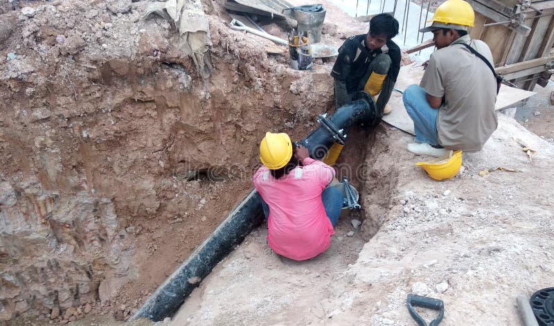 Construction workers repairing underground utility services pipe royalty free stock photography