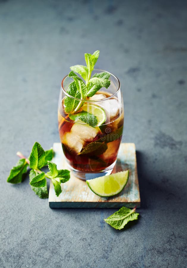 Kuba Libre i en exponeringsglasrom med cola, limefrukt, mintkaramellsidor och is royaltyfri foto