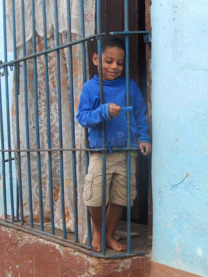 KUBANISCHER JUNGE HINTER DEM FENSTER, TRINIDAD, KUBA lizenzfreies stockfoto KUBANISCHER JUNGE HINTER DEM FENSTER, TRINIDAD, KUBA lizenzfreies stockfoto