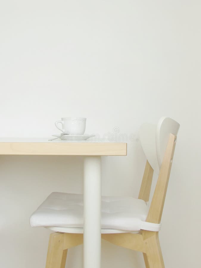 Simple interior with white walls, wooden table and chair and a coffee cup. With copy space. Simple interior with white walls, wooden table and chair and a coffee cup. With copy space.