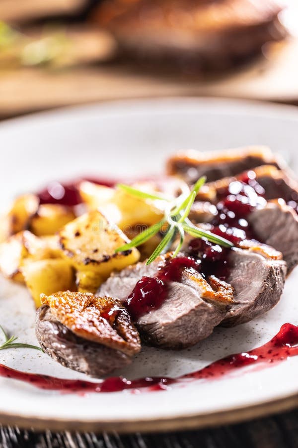 Kulinarisch zubereitete Entenbrust mit gebackenen Kartoffeln und Cranberry Kaution.