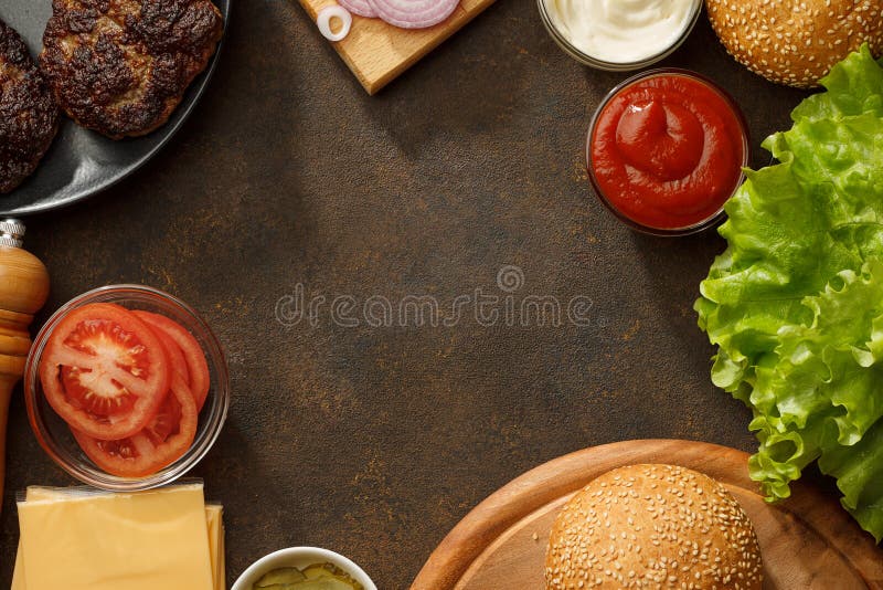 Kulinarisk bakgrund med nya ingredienser för hemlagade hamburgare på den bruna stentabellen arkivbild Kulinarisk bakgrund med nya ingredienser för hemlagade hamburgare på den bruna stentabellen arkivbild