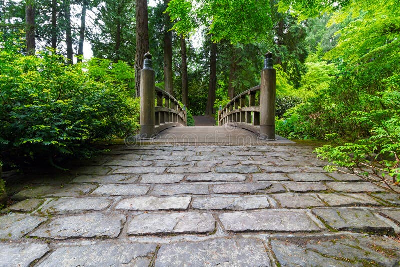 Kullerstenbana till den Wood bron i manicured japanträdgård arkivfoto Kullerstenbana till den Wood bron i manicured japanträdgård arkivfoto