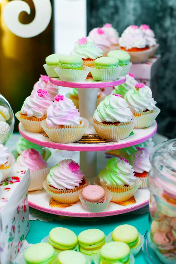 Kulöra muffiner Muffin med kräm färgrika macarons royaltyfri bild