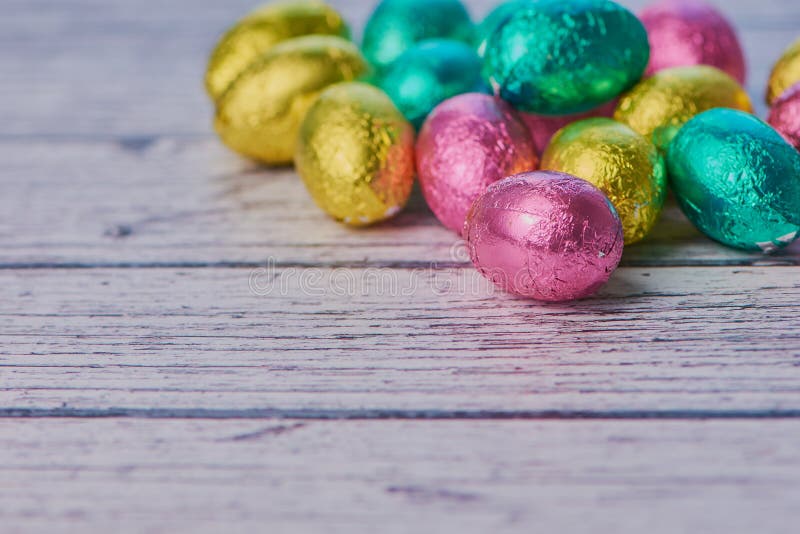 Kulöra slågna in chokladägg på vit träbakgrund arkivfoto Kulöra slågna in chokladägg på vit träbakgrund arkivfoto