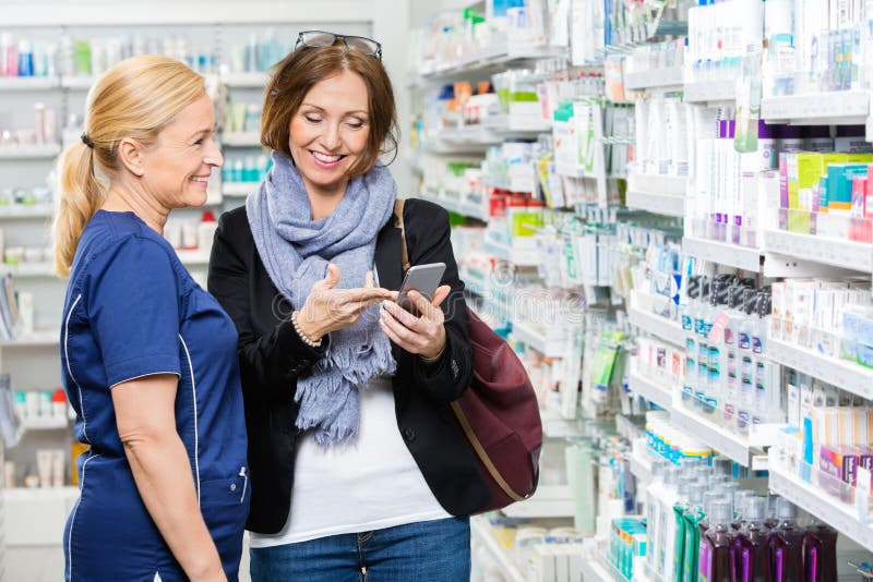 Kunde, der dem Apotheker In Handy zeigt lizenzfreie stockfotos
