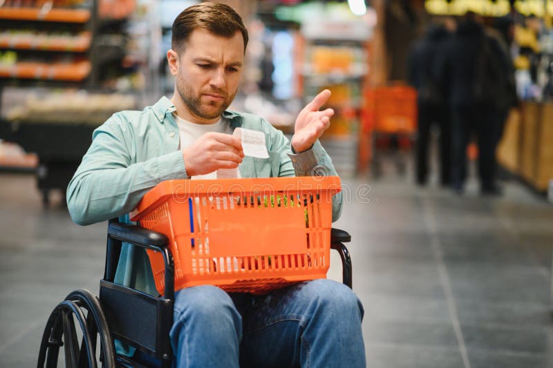 Kunde im Rollstuhl überprüft Lebensmittelgeschäft Eingang im Supermarkt lizenzfreie stockbilder