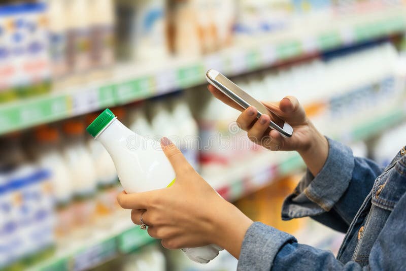 Kupujący fotografuje butelkę mleka tajemniczym zakupem. sprawdzanie jakości towarów według kodu kreskowego