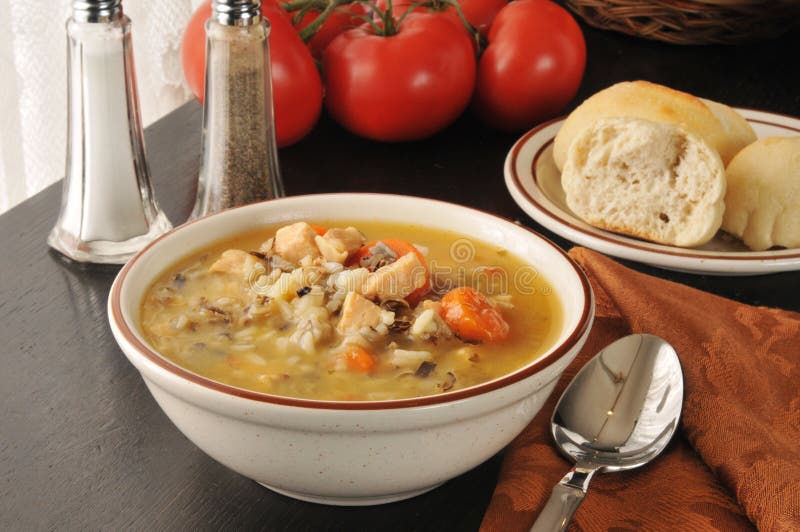 A bowl of chicken and wild rice soup with dinner rolls. A bowl of chicken and wild rice soup with dinner rolls