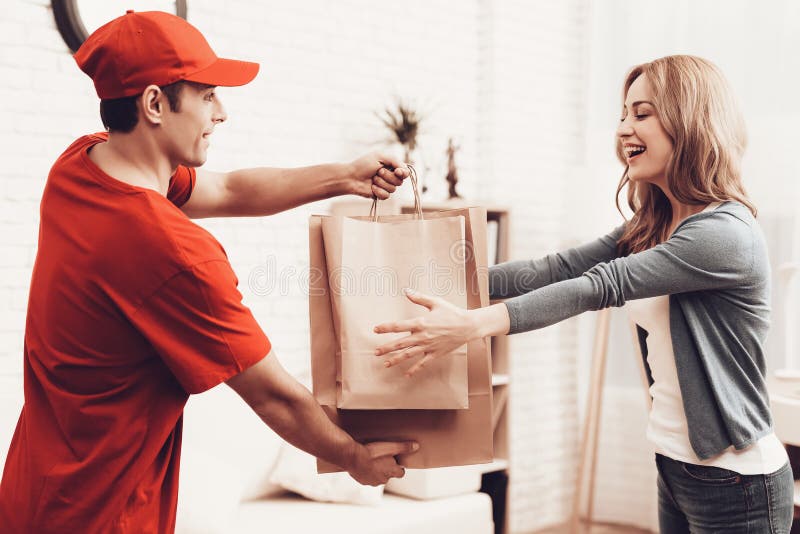 Kuriren i orange kläder ger den pappers- packen royaltyfri bild Kuriren i orange kläder ger den pappers- packen royaltyfri bild