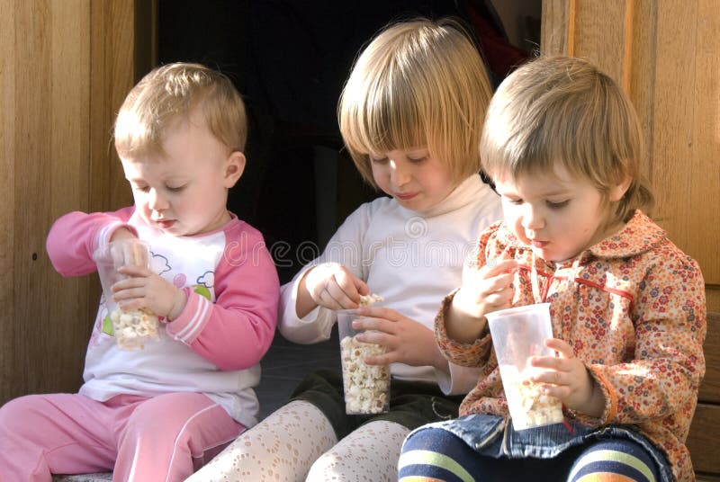 Three baby girls cousins eating popcorn during a family reunion. Three baby girls cousins eating popcorn during a family reunion