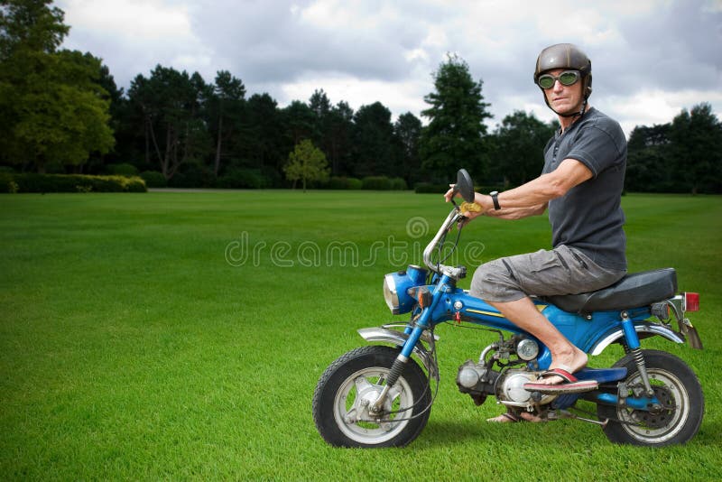 Strange biker sitting on a blue moped in countryside. Strange biker sitting on a blue moped in countryside.