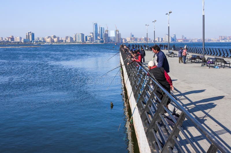 Kustpark, Baku, Azerbeidzjan - April 17, 2017 Een groep vissers vist in het Kaspische Overzees van de pijler stock foto Kustpark, Baku, Azerbeidzjan - April 17, 2017 Een groep vissers vist in het Kaspische Overzees van de pijler stock foto
