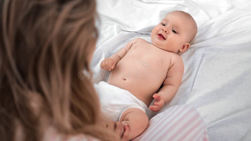 Kute baby in luier op witte bedbedwelming op moeder Shot on RED Raven 4k Cinema Camera