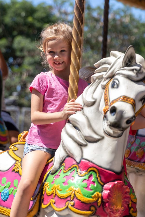 Kute kleine meid die op een carrousel rijdt in een pretpark in de zomer royalty-vrije stock afbeelding Kute kleine meid die op een carrousel rijdt in een pretpark in de zomer royalty-vrije stock afbeelding