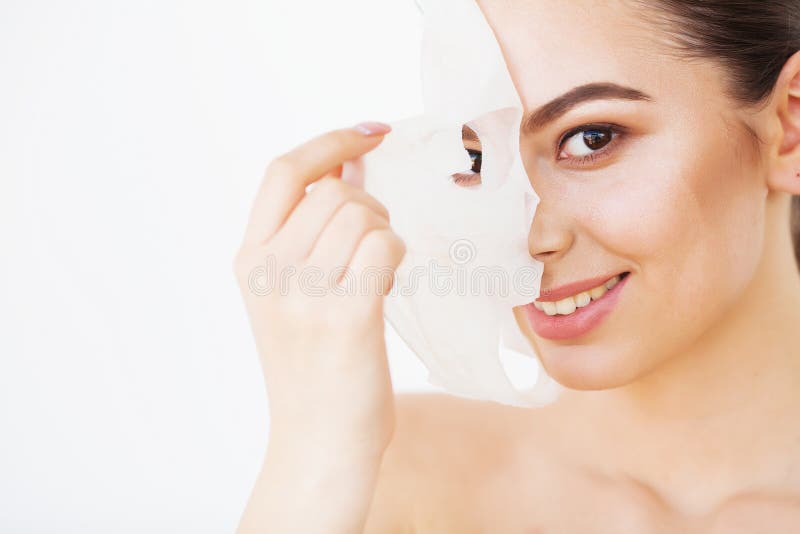 Kuuroord en verjongingsconcept Sluit omhoog geschoten van aantrekkelijke glimlachende vrouw verwijdert document masker uit gezich stock foto's Kuuroord en verjongingsconcept Sluit omhoog geschoten van aantrekkelijke glimlachende vrouw verwijdert document masker uit gezich stock foto's