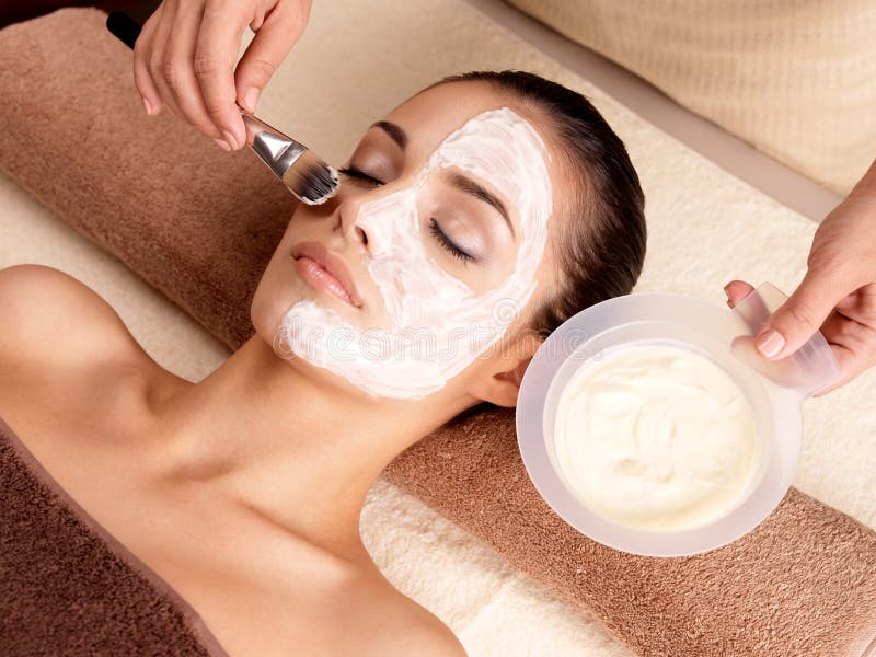 Spa therapy for young woman receiving facial mask at beauty salon - indoors. Spa therapy for young woman receiving facial mask at beauty salon - indoors