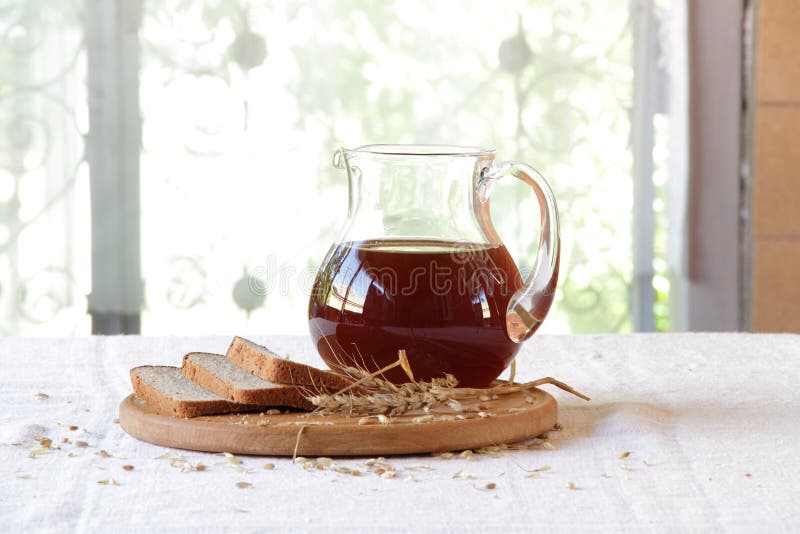 Kvass (kvas) i ett genomskinligt tillbringare- och rågbröd arkivfoto Kvass (kvas) i ett genomskinligt tillbringare- och rågbröd arkivfoto