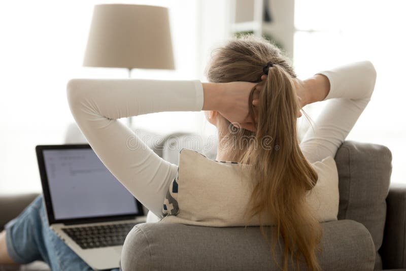 Kvinna för bakre sikt som hemma kopplar av med bärbara datorn på den bekväma soffan arkivbilder Kvinna för bakre sikt som hemma kopplar av med bärbara datorn på den bekväma soffan arkivbilder