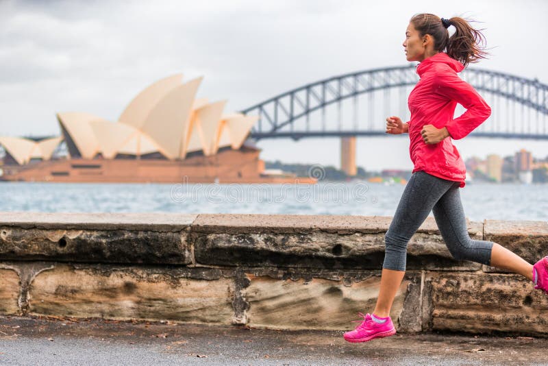 Kvinna för livsstil för löparepassform som aktiv joggar på Sydney Harbour förbi gränsmärket för turist- dragning för operahus den