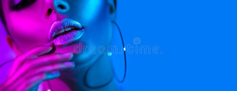 High fashion model woman in colorful bright neon lights posing in studio. Beautiful girl, trendy glowing makeup, metallic silver lips. High fashion model woman in colorful bright neon lights posing in studio. Beautiful girl, trendy glowing makeup, metallic silver lips