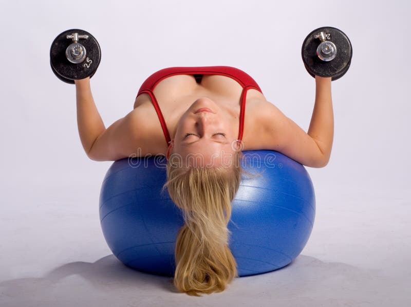 Woman lies on stability ball while exercising arms with dumbbells. Woman lies on stability ball while exercising arms with dumbbells