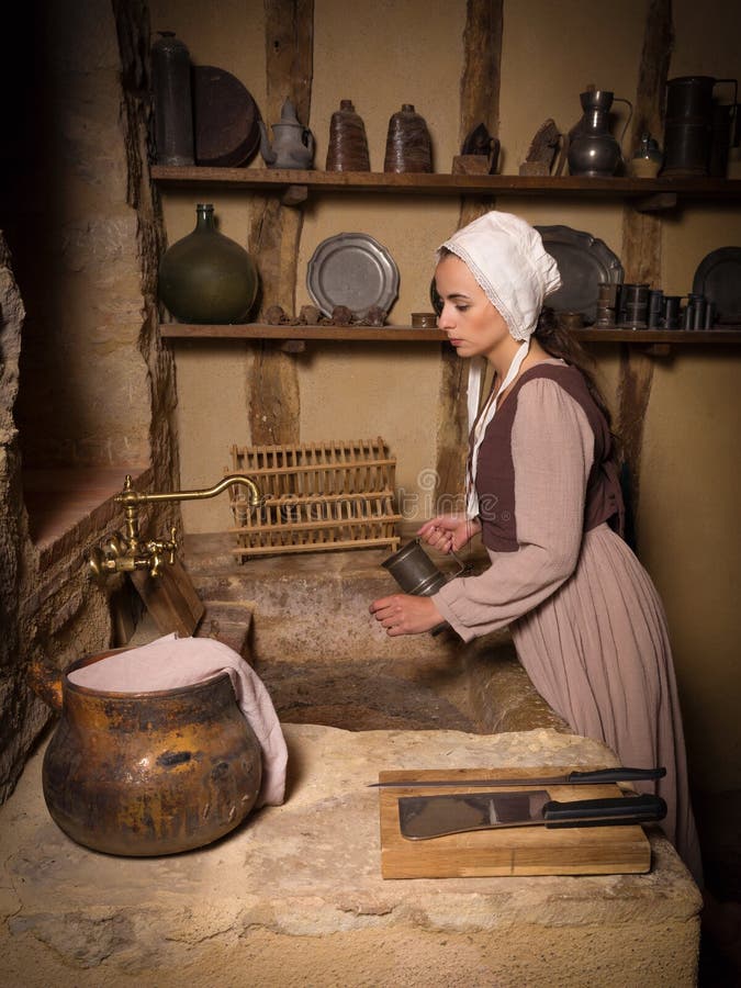 Young woman in Medieval peasant constume working in an authentic antique kitchen in a property released French chateau. Young woman in Medieval peasant constume working in an authentic antique kitchen in a property released French chateau