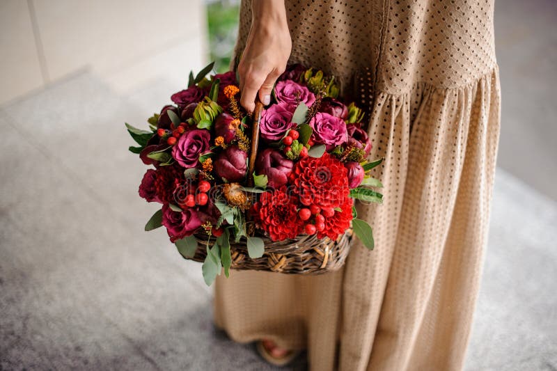 Kvinna i denlängd klänningen som rymmer en vide- korg med blommor arkivfoto Kvinna i denlängd klänningen som rymmer en vide- korg med blommor arkivfoto