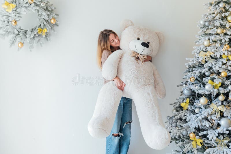 Kvinna med björnleksak och julgransträd med nya årstidsgåvor arkivbild