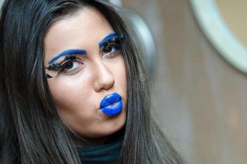 Woman with blue lipstick and eyebrows, unique makeup with feather eyelashes. Long brunette hair and smooth skin , horizontal photo. Woman with blue lipstick and eyebrows, unique makeup with feather eyelashes. Long brunette hair and smooth skin , horizontal photo