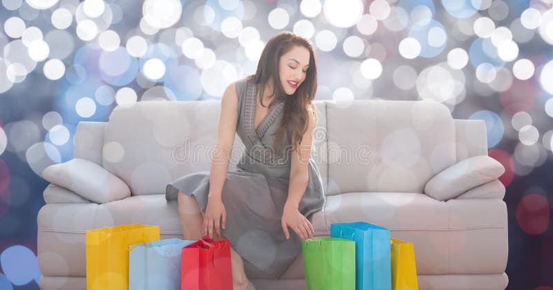 Kvinna med shoppingpåsar som sitter på soffan arkivbild Kvinna med shoppingpåsar som sitter på soffan arkivbild
