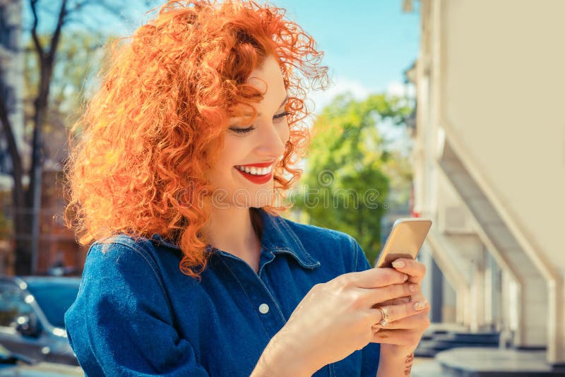 Kvinna och att le och att se hennes smsa för mobiltelefon som läser smsmeddelandet arkivbilder Kvinna och att le och att se hennes smsa för mobiltelefon som läser smsmeddelandet arkivbilder