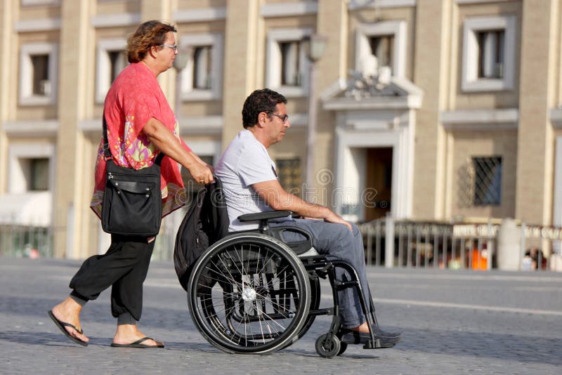 A woman brings her disabled husband around (Vatican city - Rome - Italy). A woman brings her disabled husband around (Vatican city - Rome - Italy)