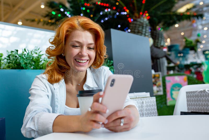 Kvinna som använder mobiltelefonen, medan dricka kaffe i kafé på shoppinggallerian royaltyfri bild Kvinna som använder mobiltelefonen, medan dricka kaffe i kafé på shoppinggallerian royaltyfri bild