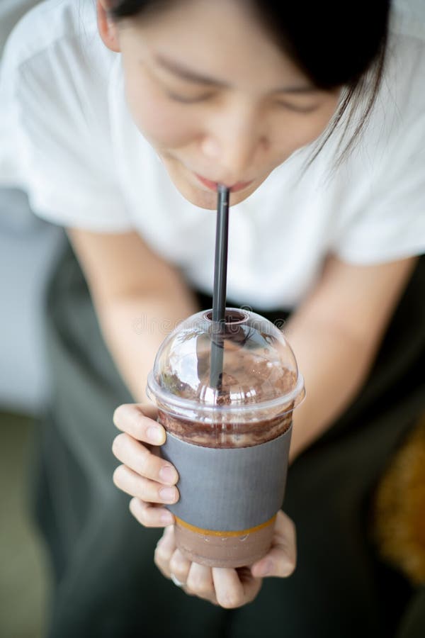Kvinna som dricker chokladmilkshake som kopplar av i kafé royaltyfri foto Kvinna som dricker chokladmilkshake som kopplar av i kafé royaltyfri foto