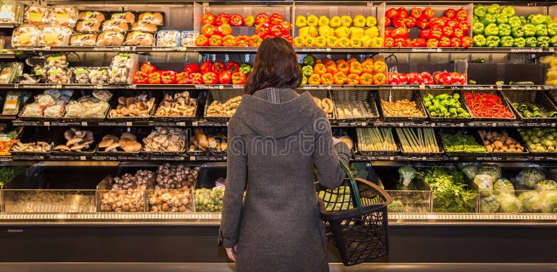 Kvinna som framme står av en rad av jordbruksprodukter i en livsmedelsbutik