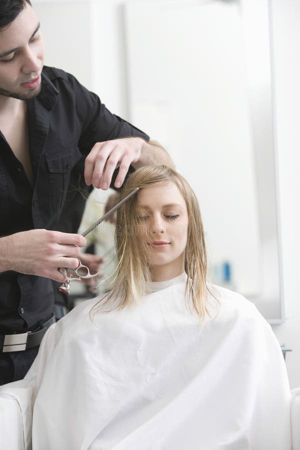 Kvinna som får frisyr från frisören At Salon arkivbilder