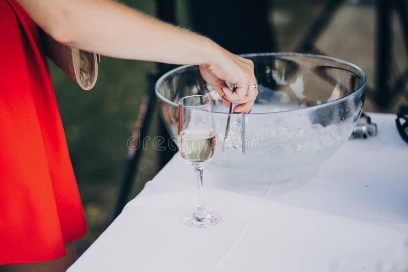 Kvinna som får is för stilfull champagnedrink på brölloptabellen royaltyfri foto Kvinna som får is för stilfull champagnedrink på brölloptabellen royaltyfri foto