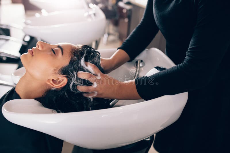 Kvinna som får hår shampooed på salongen