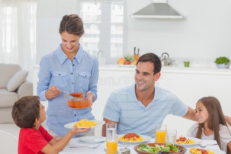 Kvinna som ger pastasås till hennes son arkivfoto Kvinna som ger pastasås till hennes son arkivfoto