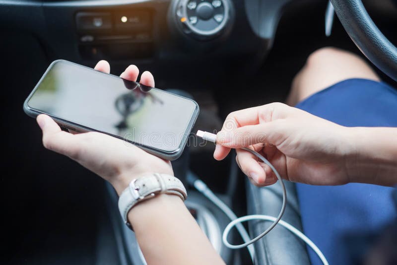 Woman charging smartphone in car. Technology and transportation concepts. Woman charging smartphone in car. Technology and transportation concepts.