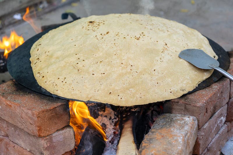 Kvinna som lagar mat traditionellt indiskt br? d, stor chapati som lagar mat p? ? ppen brand, Indien royaltyfria foton