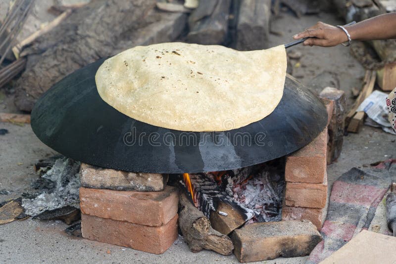 Kvinna som lagar mat traditionellt indiskt br? d, stor chapati som lagar mat p? ? ppen brand, Indien arkivfoton
