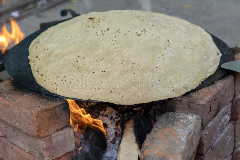 Kvinna som lagar mat traditionellt indiskt br? d, stor chapati som lagar mat p? ? ppen brand, Indien arkivfoto