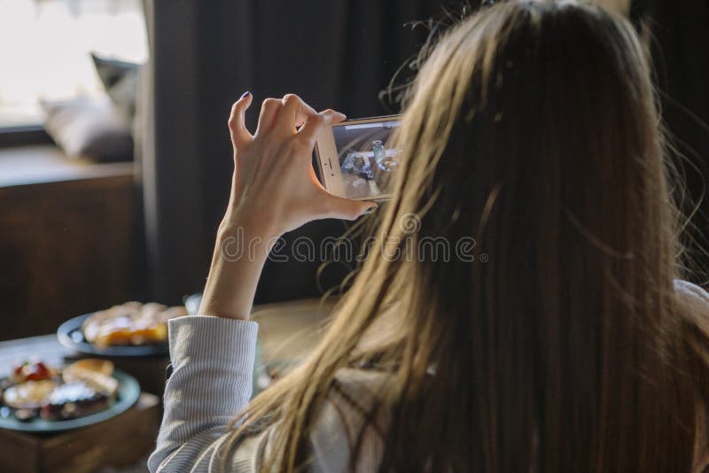 Kvinna som photograhing på hennes telefon en söt stång av läckra kakor arkivfoto Kvinna som photograhing på hennes telefon en söt stång av läckra kakor arkivfoto